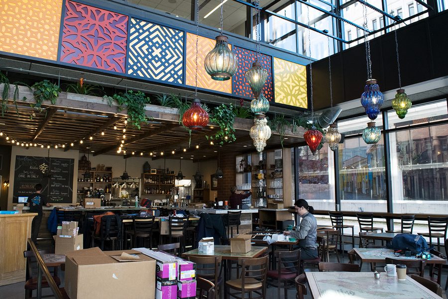 The ROAM dining room: tall windows, a wall of vivid patterned tile panels, coloured glass lanterns strung overhead and marble tables below.
